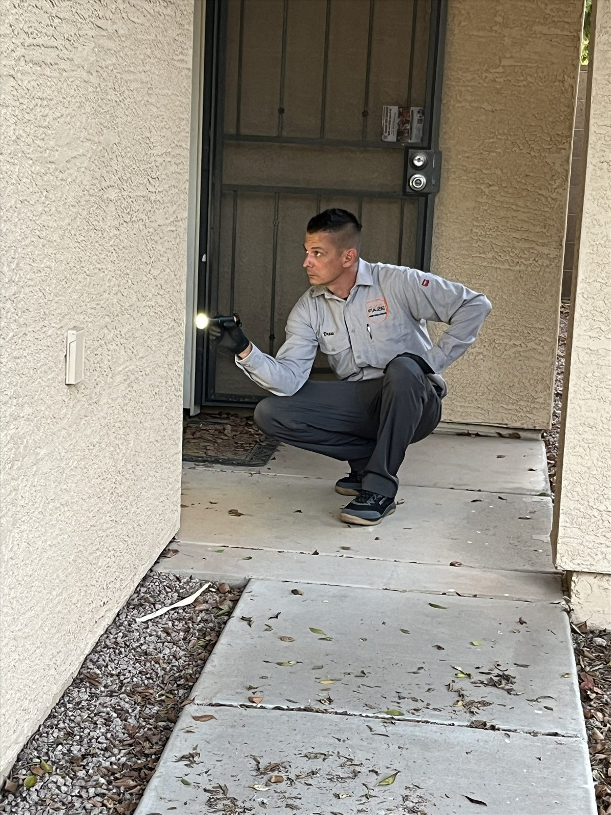 Faze Pest Solutions flashlight inspection near a front entryway