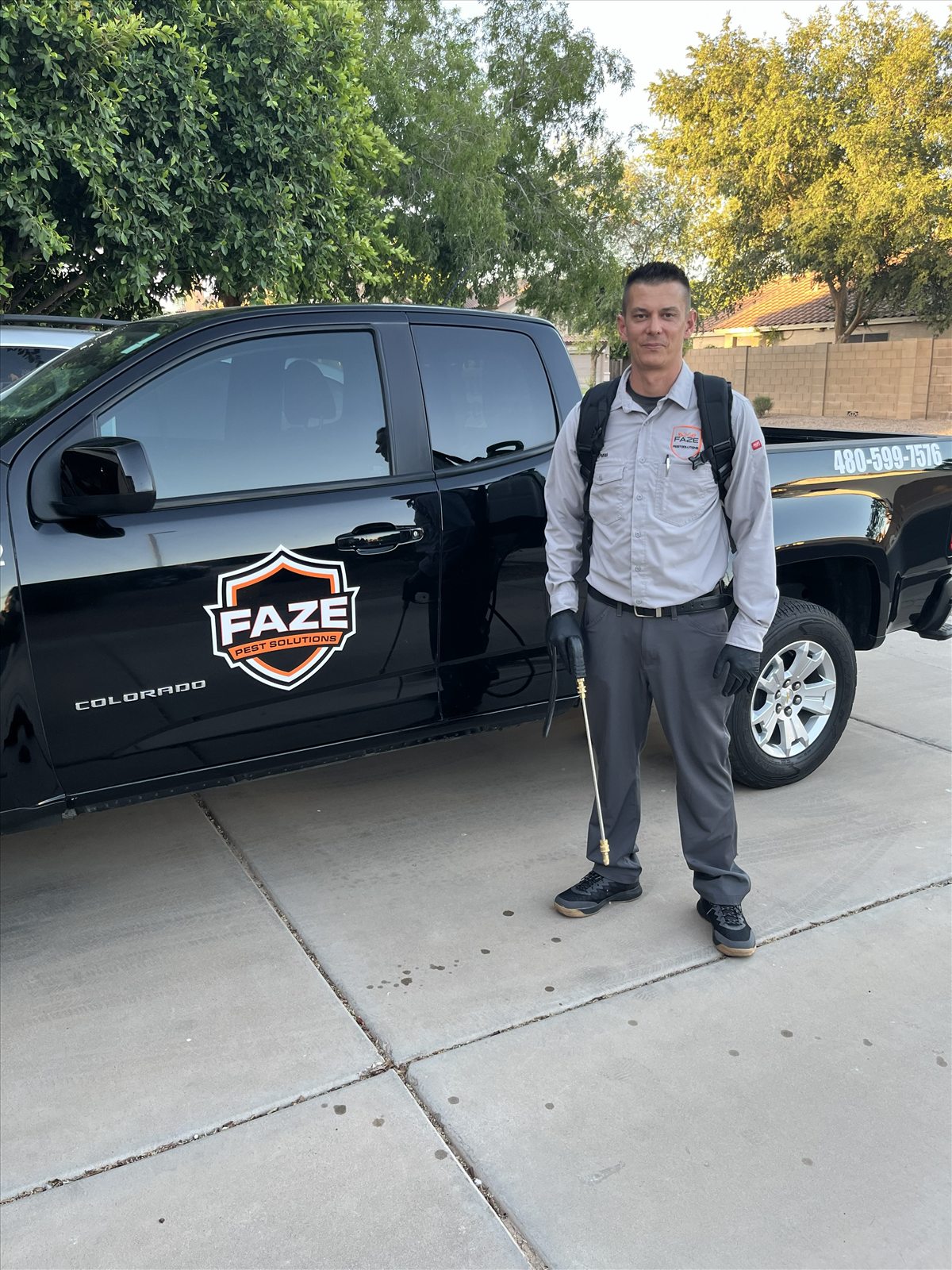 Drew from Faze Pest Solutions with backpack sprayer beside branded truck