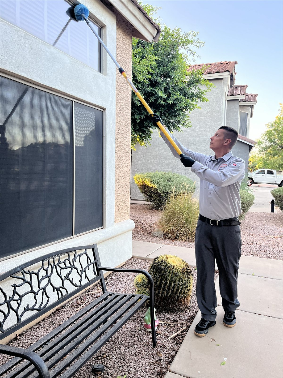 Faze Pest Solutions brushing spider webs from home eaves